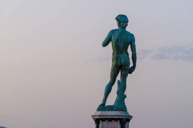 Tepe ve günbatımı gökyüzünde yer alan eski heykel