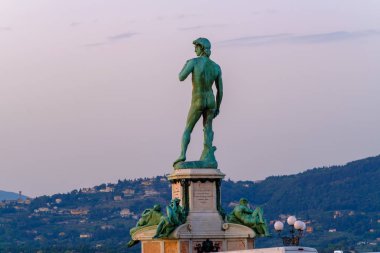 Tepe ve günbatımı gökyüzünde yer alan eski heykel