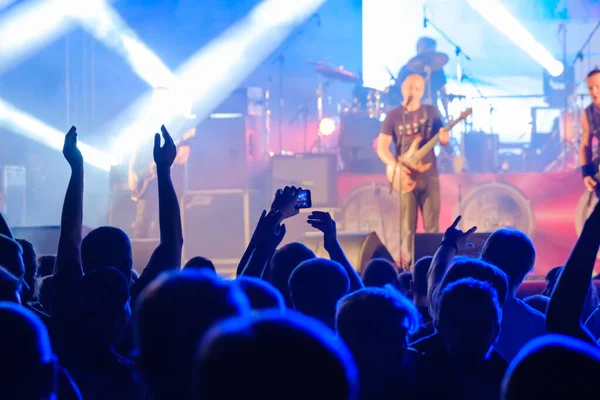 Fans i mörk neon lyssnar på rockband på scen — Stockfoto