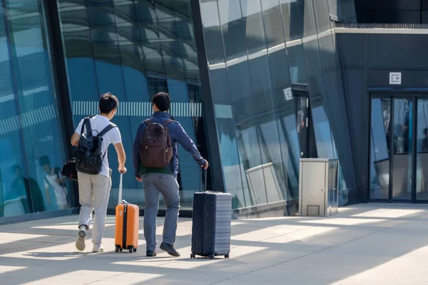 Two traveler guys go to the airport entrance with suitcases — Stockfoto