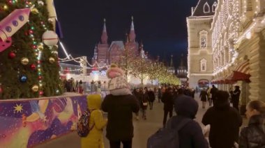 İnsanlar akşamları Noel için aydınlatmalarla süslenmiş şekilde sokaklarda yürür.