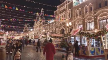 İnsanlar akşamları Noel için aydınlatmalarla süslenmiş şekilde sokaklarda yürür.