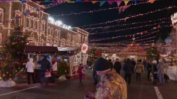 Люди ходять по вулицях, прикрашених освітленням до Різдва ввечері. — стокове відео