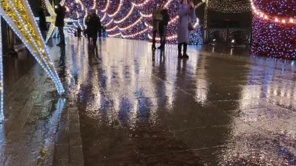 人々は夜にクリスマスのための照明で飾られた通りを歩く — ストック動画