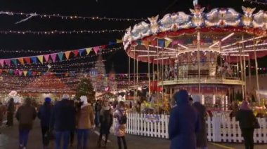 İnsanlar Noel pazarında atlıkarıncaya biniyor.