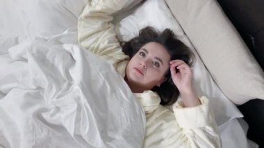 Young girl tossing and turning in bed, top view