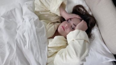 Young girl tossing and turning in bed, top view