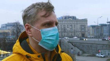 Koruyucu tıbbi maske takan bir adamın kafa görüntüsü.