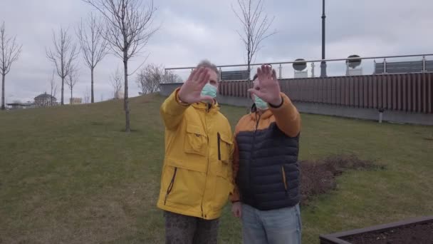 의료용 마스크를 쓴 두 남자가 이 병의 확산에 대해 항의하며 손을 들고 있다 — 비디오