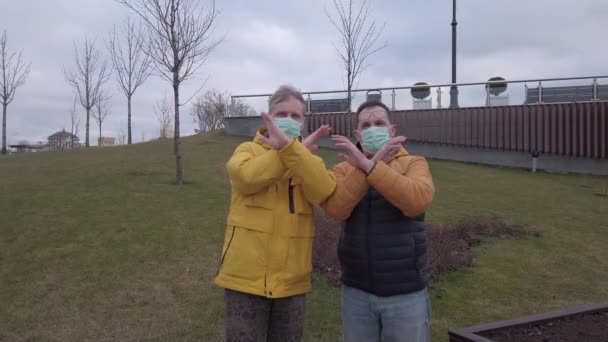 Dwóch mężczyzn w maskach medycznych podnosi ręce w proteście przeciwko rozprzestrzenianiu się choroby. — Wideo stockowe