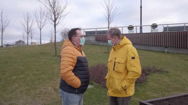 Two men in medical masks are talking outdoors — Stock Video