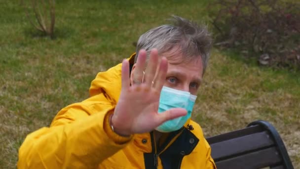 Man wearing protective medical mask shows he does not want be filmed — Stockvideo