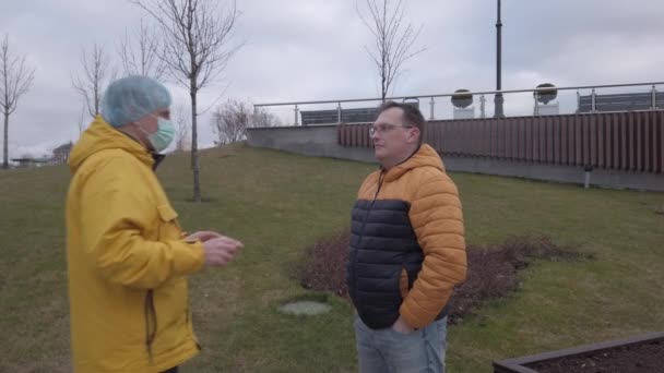 One man puts a protective medical mask on the face of another — Stockvideo