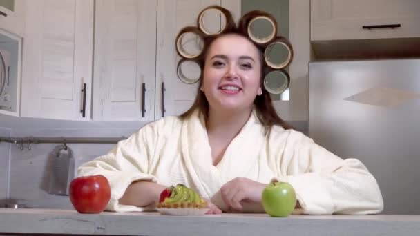 Plus size girl with curlers on her head recording a video blog — Stock video