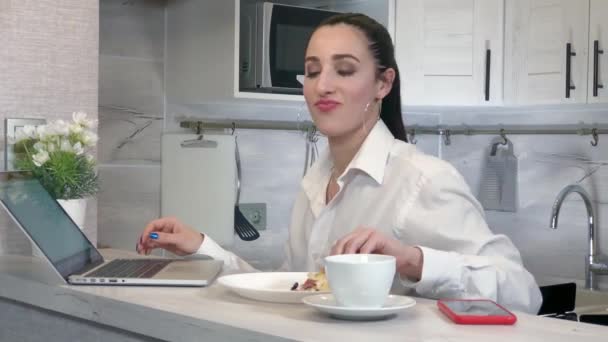 Young business woman eats a piece of pizza in the kitchen — Stock video