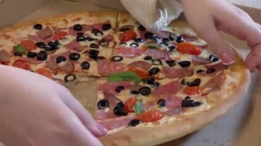 Female hands take a large piece of pizza