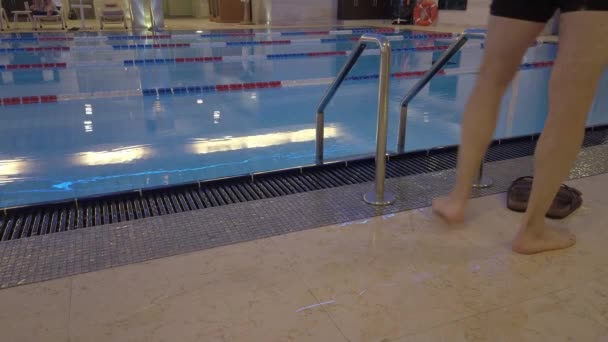 Hombre desciende las escaleras a la piscina — Vídeo de stock