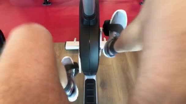 Homem POV no ginásio pedala uma bicicleta de exercício — Vídeo de Stock