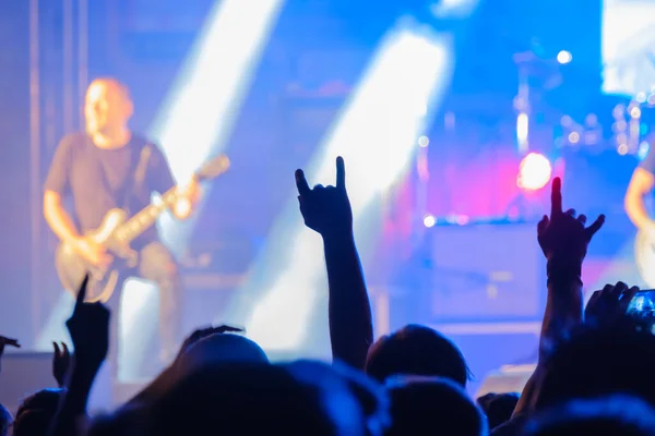 Fanoušci v tmavém neonu poslouchají rockovou kapelu na pódiu — Stock fotografie