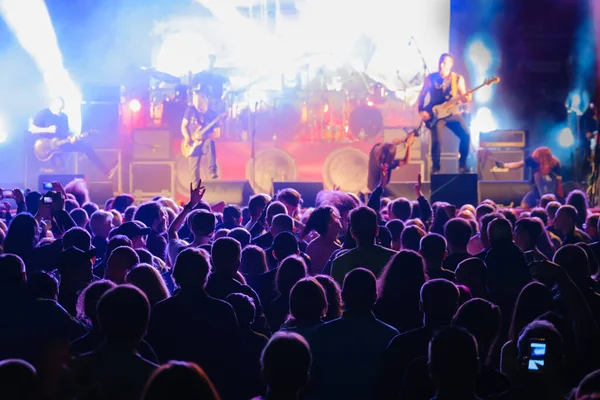 Fani w ciemnym neonie słuchający rockowego zespołu na scenie — Zdjęcie stockowe