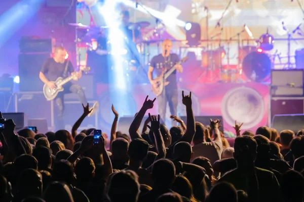 Fans in dark neon listening to rock band on stage — Stock Photo, Image