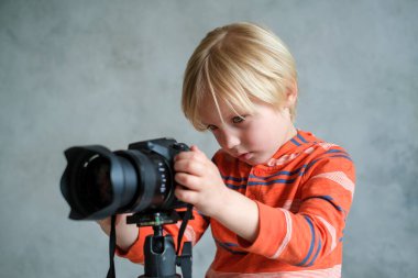 Çocuk profesyonel fotoğraf makinesiyle oynuyor.