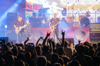 Karanlık neonlu hayranlar sahnede rock grubunu dinliyor.