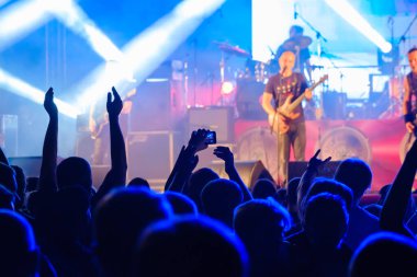 Taraftarlar sahnede rock grubu dinliyor