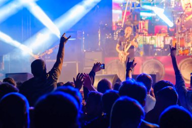 Taraftarlar sahnede rock grubu dinliyor