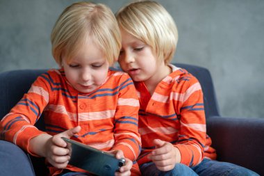 Kardeşler izliyor, oynuyor ya da akıllı telefondan bir şeyler öğreniyor.