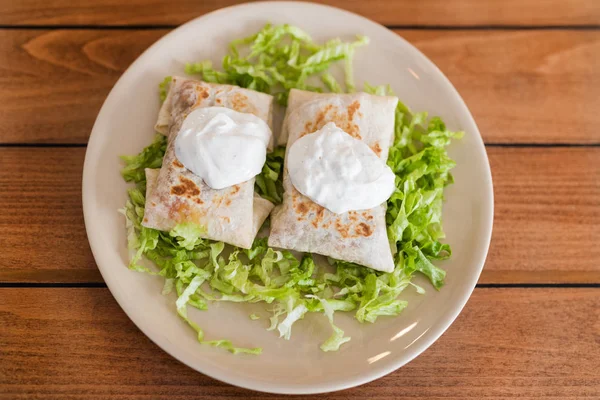 Üstüne krema ile salata üzerinde Chimichanga.