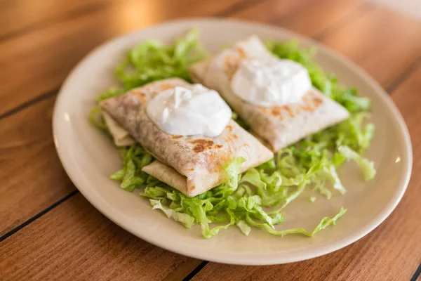 Üstüne krema ile salata üzerinde Chimichanga.