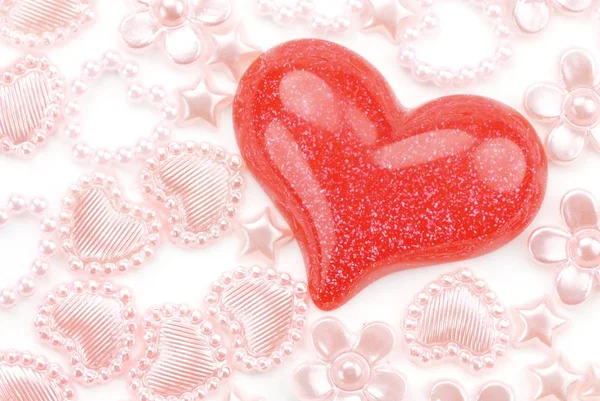 Glänzend rotes Herz mit Schmuckstücken auf dem weißen — Stockfoto