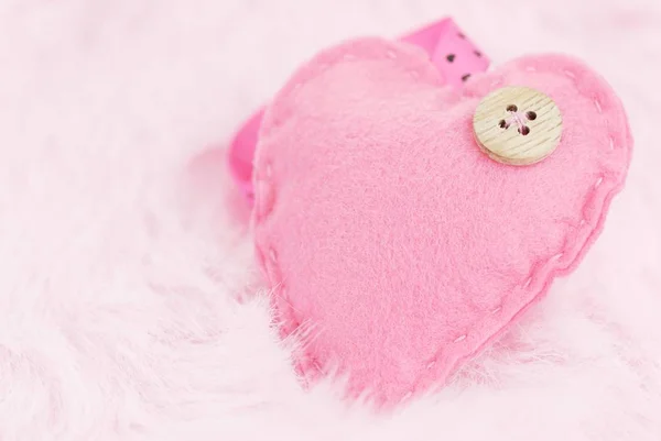 Розовое сердце с пуговицей на фоне пера — стоковое фото