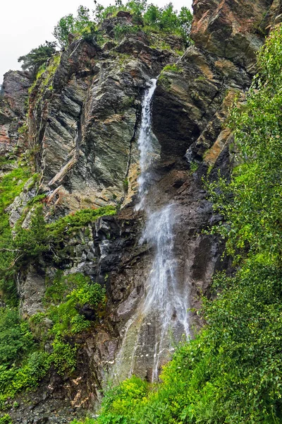 Vandfald flyder ned ad en stejl klippe i bjergene - Stock-foto