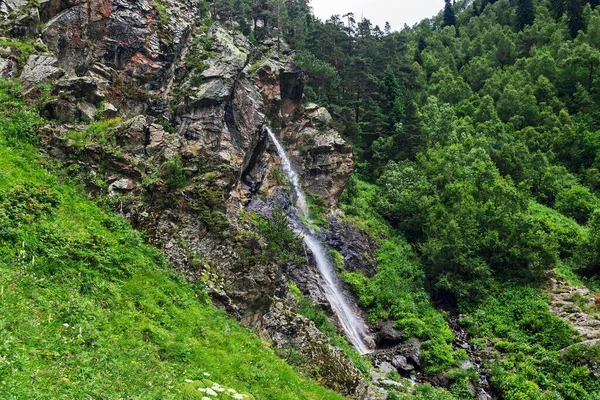 Vandfald flyder ned ad en stejl klippe i bjergene - Stock-foto