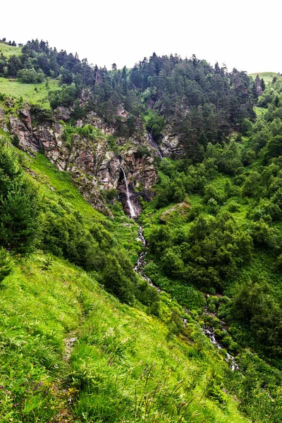 Waterfall flowing down a steep cliff in the mountains — Stok fotoğraf