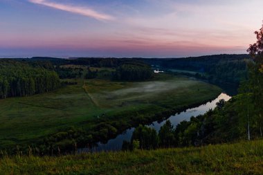 Gün batımında yüksek bir tepeden nehir ve orman