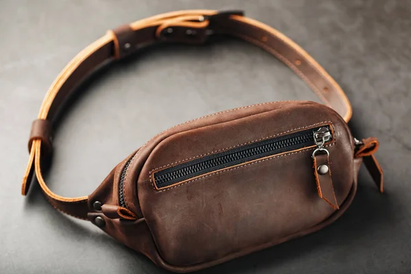 Handmade genuine brown leather on a dark background Brown belt bag. Elegant brown bag with a zipper