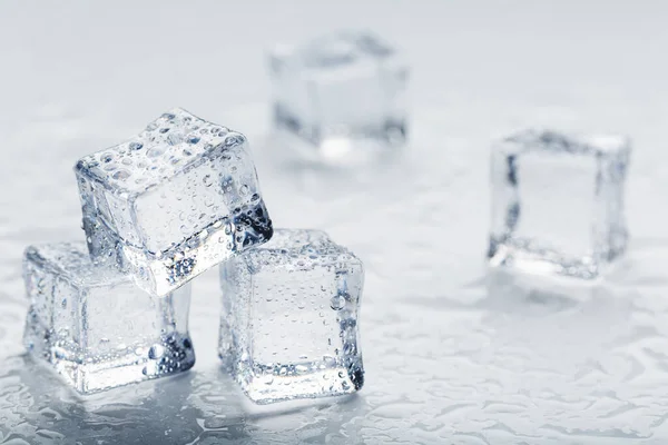 Ice cubes in the form of a pyramid with water drops close - up in macro on a white background.