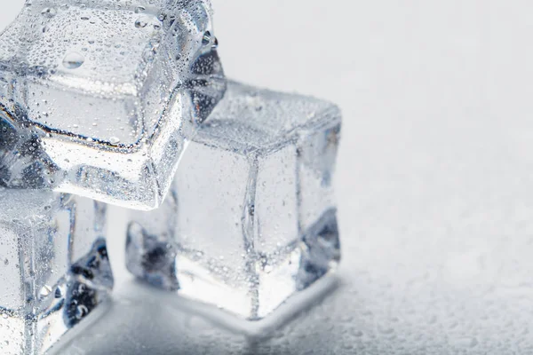 Ice cubes in the form of a pyramid with water drops close - up in macro on a white background. Refr