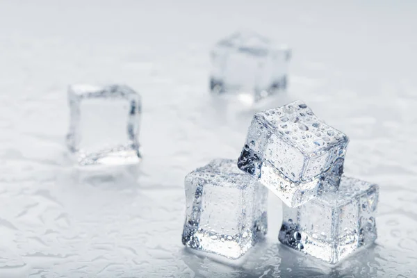 Ice cubes in the form of a pyramid with water drops close - up in macro on a white background. Refr