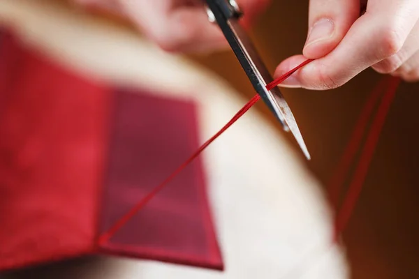 A leather craftsman works with leather. Sews leather goods. Making things handmade. Women's hands with a needle, thread, scissors and a blowtorch. Close up