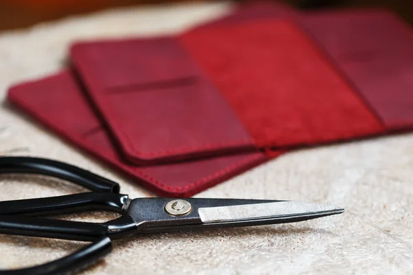 A leather craftsman works with leather. Sews leather goods. Making things handmade. Women\'s hands with a needle, thread, scissors and a blowtorch. Close up