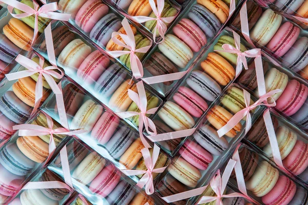Macaroni cookies of different colors in a package with a bow, a lot of boxes with cookies in the form of texture. Full screen, top view