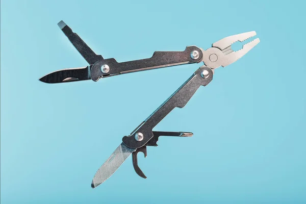 The multitool multi-function tool hovers on a blue background. The concept of an expanded multi-tool with free space. Clipping path included isolate
