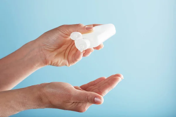 A bottle of Disinfectant gel in your hands on a blue background. Antiseptic treatment of hands from bacteria Sanitizer. Free space, isolate.