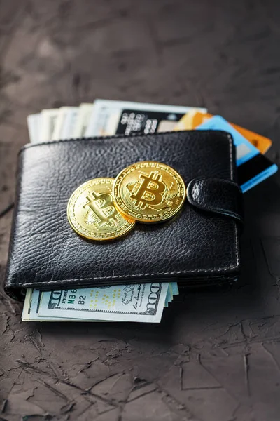 Eine schwarze Brieftasche mit Dollars, E-Cards und Bitcoins auf schwarzem Hintergrund. Symbol für Wohlstand und Wohlstand. Nahaufnahme — Stockbild Eine Schwarze Brieftasche Mit Dollars Cards Und Bitcoins Auf Schwarzem — Stockfoto
