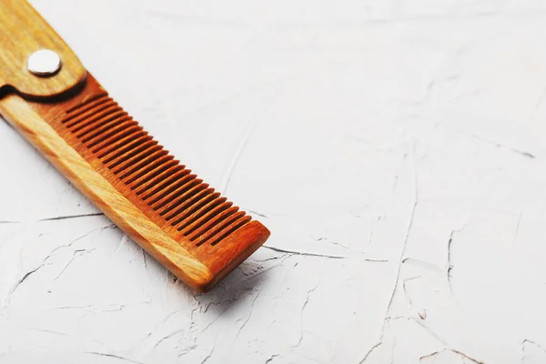 Folding wooden comb on a gray background. Close up.