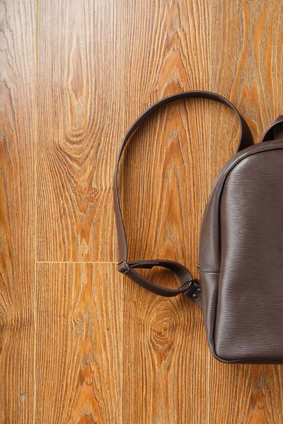Backpack made of brown genuine leather on a wooden background. Classic style, handmade.
